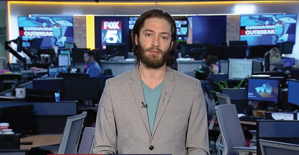 Brian Larsen standing in a Fox 5 newsroom during a live broadcast interview